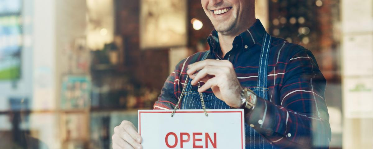 Gastwirt hängt ein Open-Schild an die Tür seiner Gaststätte