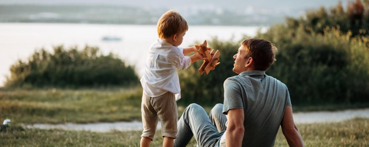 Vater und Kind spielen gemeinsam auf einer Wiese am See