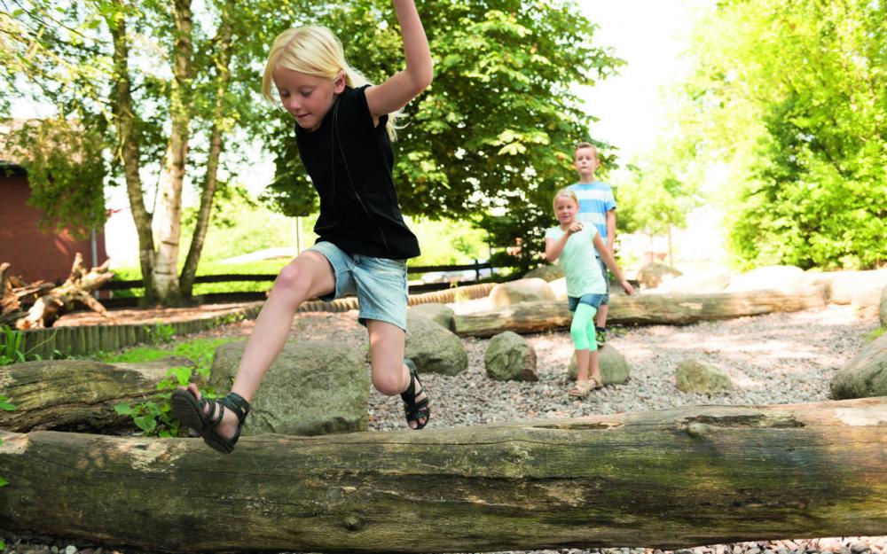 Grundschulkinder spielen auf einem naturnahen Außengelände