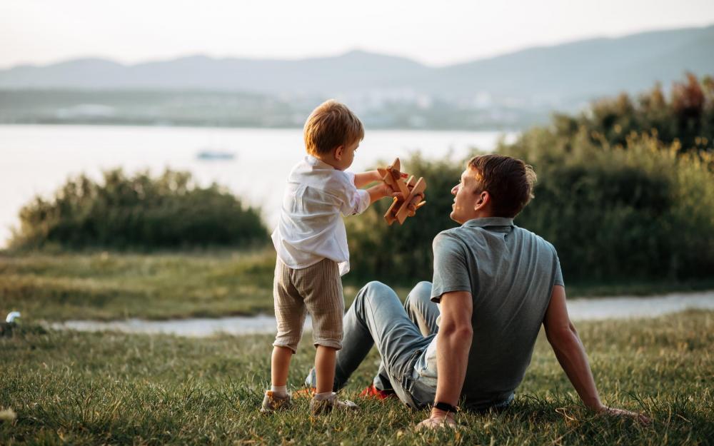 Vater und Kind spielen gemeinsam auf einer Wiese am See