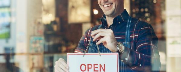 Gastwirt hängt ein Open-Schild an die Tür seiner Gaststätte