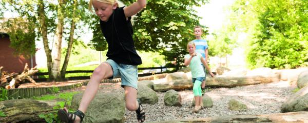 Grundschulkinder spielen auf einem naturnahen Außengelände